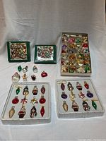 Full view of the assortment with multiple packs and trays of miniature glass Christmas ornaments in various shapes and colors.