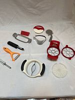 Kitchen utensils including peelers, cutters, slicers arranged on white background, showing all items visually for identification.