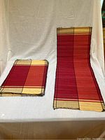 Photo showing folded placemats stacked on the left and the table runner rolled out on the right against a white backdrop.