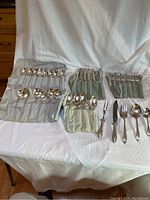 Full view of all flatware pieces arranged and partially sheathed in cloth holders showing variety and quantity