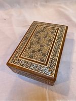 Top angle showing intricate geometric inlaid design with mother of pearl and cow bone on wooden rectangular box.