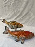 Two matched painted Asian wooden koi fish statues, side view showing scale detail and coloration.