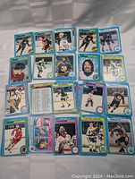 Photo showing multiple 1979-80 OPC hockey cards laid out, featuring various players from teams such as Vancouver Canucks, Chicago Black Hawks, Edmonton Oilers, Washington Capitals, Buffalo Sabres, Hartford Whalers, and New York Rangers. Cards show player photos on fronts with blue borders and team logos.