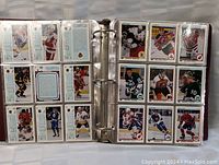 Open binder showing two pages of hockey cards arranged in clear plastic sleeves, each card detailed with player's photo and stats