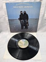 Vinyl record with cover and partial inner sleeve on fabric surface. Album cover is blue with photo of Seals and Crofts standing at beach.