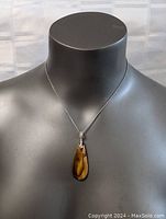 Front view of mannequin bust wearing sterling silver chain with brown gradient stone pendant.