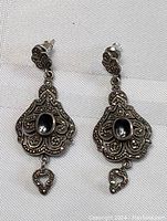 Full pair of sterling silver dangle earrings with intricate Gothic design and black stones.
