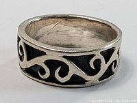 Close-up photo of sterling silver modernist ring showing black enamel with silver swirling motif on the outer band.