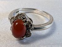 Close-up front angle of sterling silver ring with reddish-brown tourmaline cabochon and decorative silver setting.