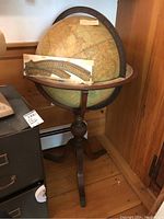 Full view of globe and carved wood tripod stand with measuring rulers propped on horizon ring