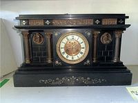 Front view of the black marble mantle clock showing the full clock with columns and decorative relief medallions