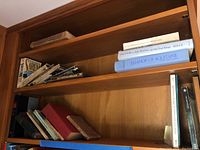 Books arranged on wooden shelves, showing varied titles and spines