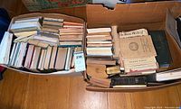 Two boxes filled with assorted vintage books, showing various sizes and some rodent damage.