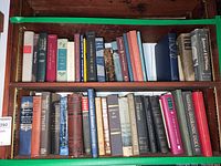 Books on two shelves showing a wide collection of vintage and antique titles in various conditions and colors, predominantly hardcover.