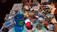 Overview of a table crowded with various vintage costume jewelry, collectibles, vanity items, toys, games, seashell collections, and home goods including boxes, containers, and decorative pieces.