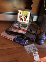 Photo of stacked games and puzzles including Husker DU game and boxes, auto cards, and a large King of Hearts playing card prop.