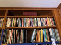 Two wooden shelves filled with many hardcover books, some with visible titles.