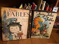 Photo of two hardcover books: Aesop's Fables and Fairy Tales and Fables with colorful illustrated covers.