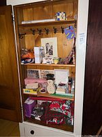 Wooden shelving unit with multiple shelves holding holiday decorations, crafts, wall art, and assorted items described in detail