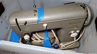 Side view of Pfaff 60 sewing machine showing the main body, tension dial, and power cord secured with blue tape.