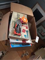 Box filled with board games including Sorry, Monopoly, and Cribbage boxes visible with some wear.