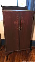 Front closed view of the vintage wooden sheet music cabinet with carved detailing and aged finish.