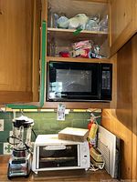 Wide view showing Sharp microwave above counter with cutting boards and Sunbeam toaster oven below
