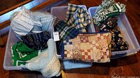 Three plastic bins with multiple folded blankets including green and white L.L.Bean woven blankets, a patchwork antique baby quilt, and assorted woven and fleece blankets in various colors and patterns.
