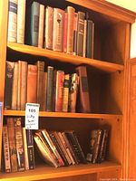 Four wooden shelves filled with vintage books, some stacked and some upright.