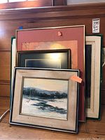 Group photo showing multiple framed artworks stacked, including 'Winter Stream' with visible black frame and beige mat.
