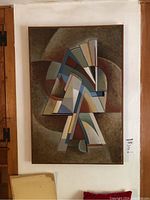 Abstract painting featuring geometric shapes in muted colors within a wooden frame, hung on a wall.