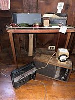 Wood shelf with metal boxes, collectible jars, vintage radios, and a vintage clock