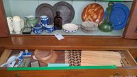 Wide view showing multiple items including Wedgwood jasperware cups and saucers, pewter plates, amber and green glass decanters, various ceramic dishes, and pottery bowls.