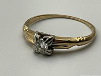 Front-facing view showing round diamond in white gold prong setting and yellow gold band