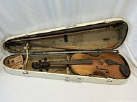 Antique violin with original case open showing violin, bows, and an accessory box inside.