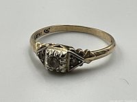 Front angle showing the 10k yellow gold band and 18k white gold setting with three diamonds, clearly showing the Art Deco design.