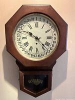 Front view of octagonal oak case wall clock with lower regulator door.