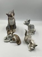 Four cat figurines arranged front view on neutral background