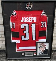 Front view of framed display containing autographed red Team Canada jersey, photo and plaque