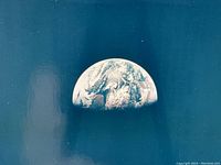 Close-up of Earthrise image showing half of Earth above lunar horizon on glossy print