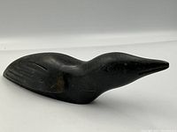 Side view of signed soapstone loon carving showing bird profile with carved wings and elongated head.