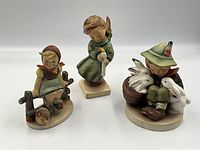 Photo of all three Hummel figurines together, showing boy with bunnies, heavenly angel, and Just Resting girl.