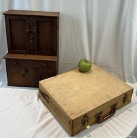 Frontal view of miniature oak wood hutch cabinet standing beside closed wooden artist's box with green apple on top for size reference.