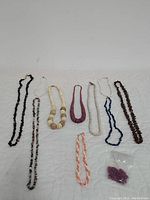 Full view of all ten handmade beaded necklaces including various colors and bead types.