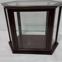 Front and side view of dark brown wooden display case with clear glass panels and hexagonal shape.
