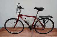 Side view of red Trek Multitrack 7300 hybrid bike showing frame, wheels, seat, and kickstand