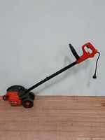 Full side profile view of the Black and Decker Electric Edge Hog lawn edger showing long handle, power switch, and wheels.