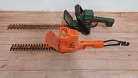 Photo showing two Black and Decker electric hedge trimmers side-by-side, highlighting their blades and handles.