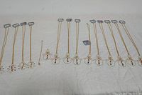 Photo of 9 gold-tone snowman necklaces laid out side by side with white background showing red hats and buttons