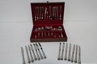 Full view of the 12-piece flatware set displayed with the wooden case open, showing both upper and lower compartments and extra knives arranged outside the case.